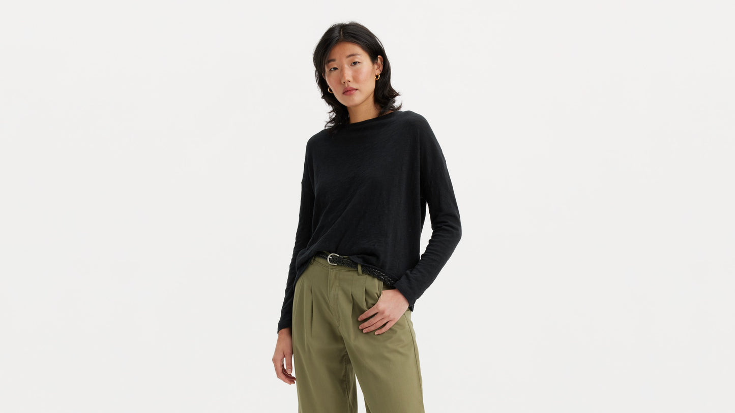 Woman in black long-sleeve top with olive pleated pants