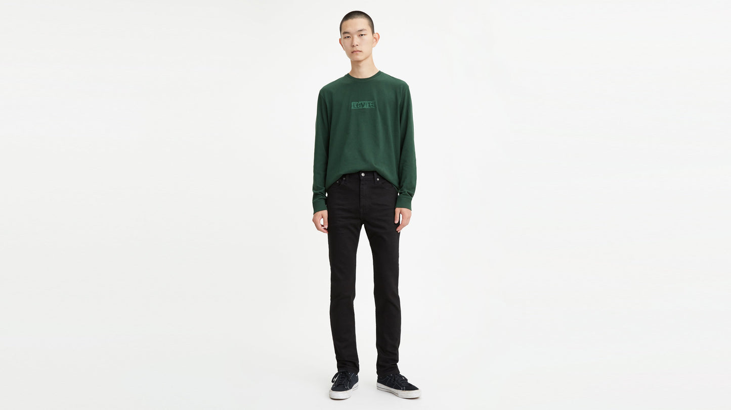 Front view of a man in black skinny jeans paired with green sweatshirt & sneakers