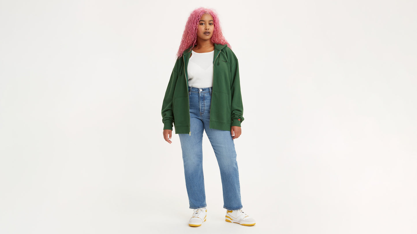 Woman in light-blue Levi's jeans, white tank top and green hoodie