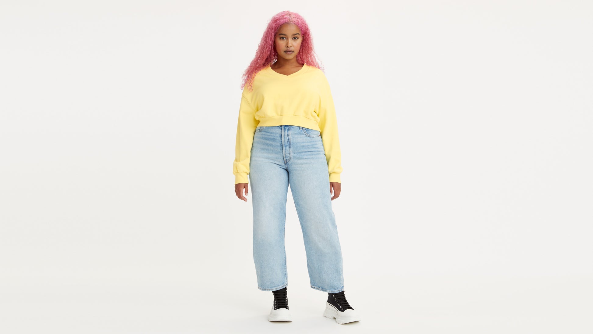 Woman in light-wash Levi's jeans and yellow sweatshirt