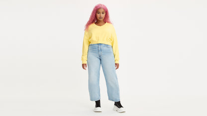 Woman in light-wash Levi's jeans and yellow sweatshirt