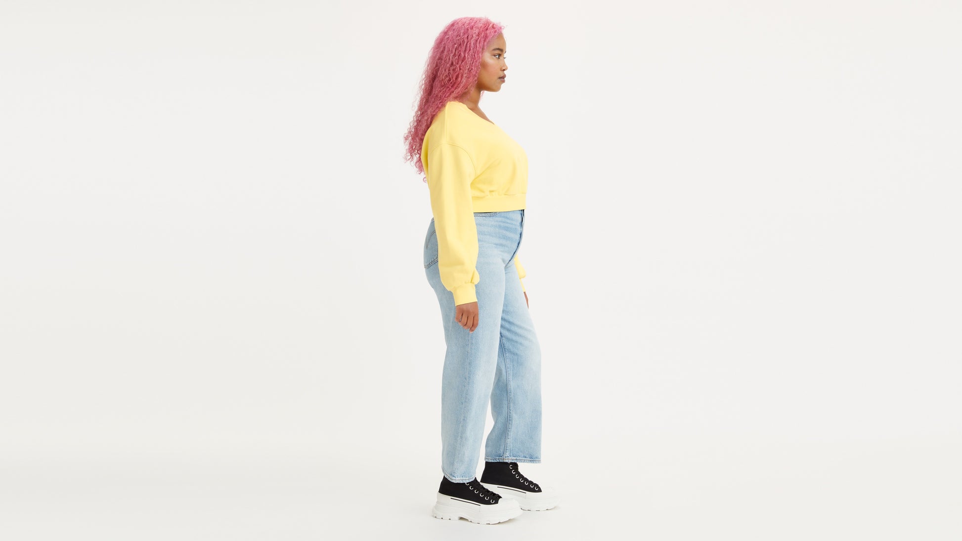 Woman in light-wash Levi's jeans with yellow sweatshirt