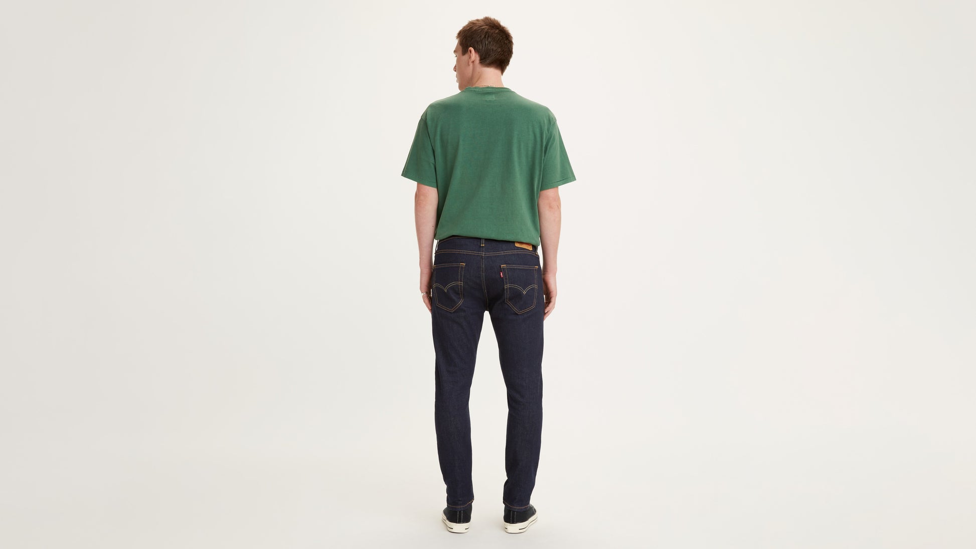 Men's dark indigo Levi's jeans and green tee back view