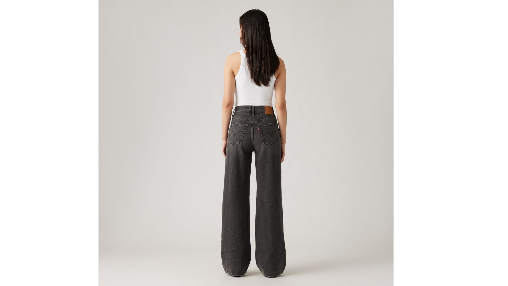 Woman in Levi's black wide-leg jeans and white tank top