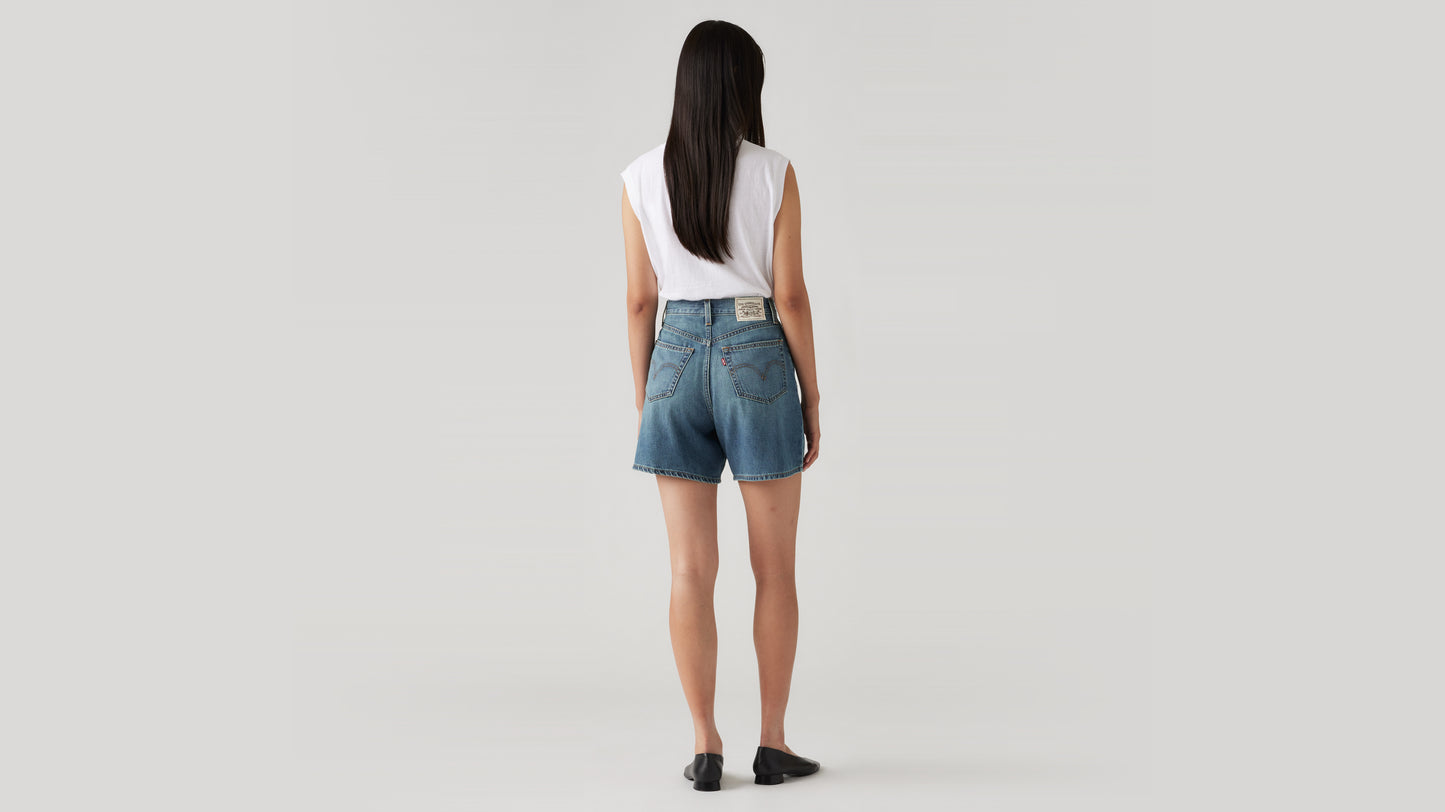 Woman in white tank and denim shorts back view
