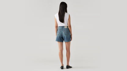 Woman in white tank and denim shorts back view