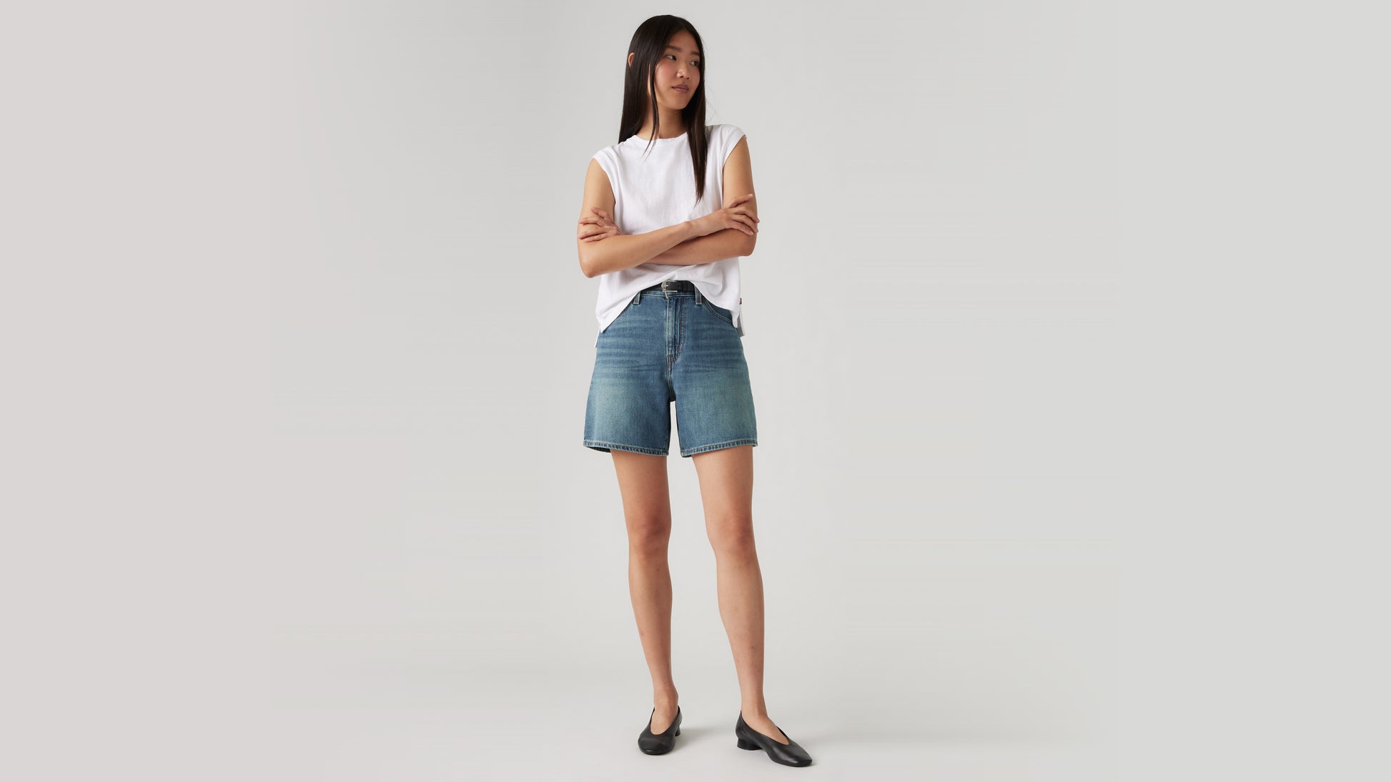 Woman wears high-rise Levi's denim shorts and flats