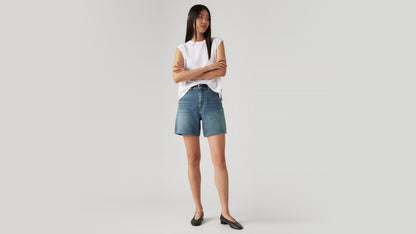 Woman wears high-rise Levi's denim shorts and flats