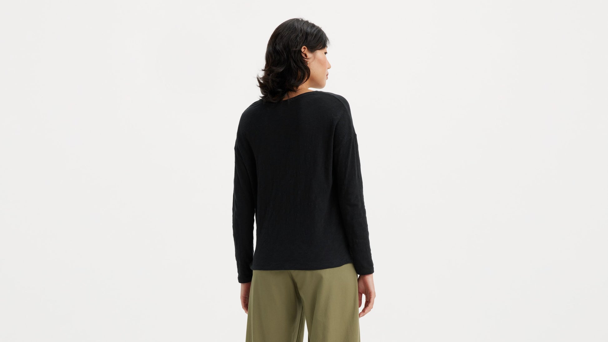 Woman in black long-sleeve top with olive-green pants