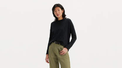 Woman in black long-sleeve top with olive pleated pants