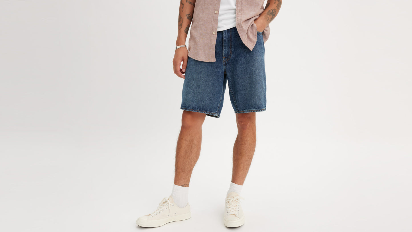 Cropped front view of man in Levi’s 468 Shorts with pink shirt, whitee tee, & sneakers