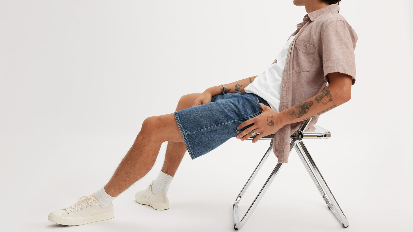 Side view of Levi’s 468 Shorts in dark wash blue with shirts & sneakers, worn seated