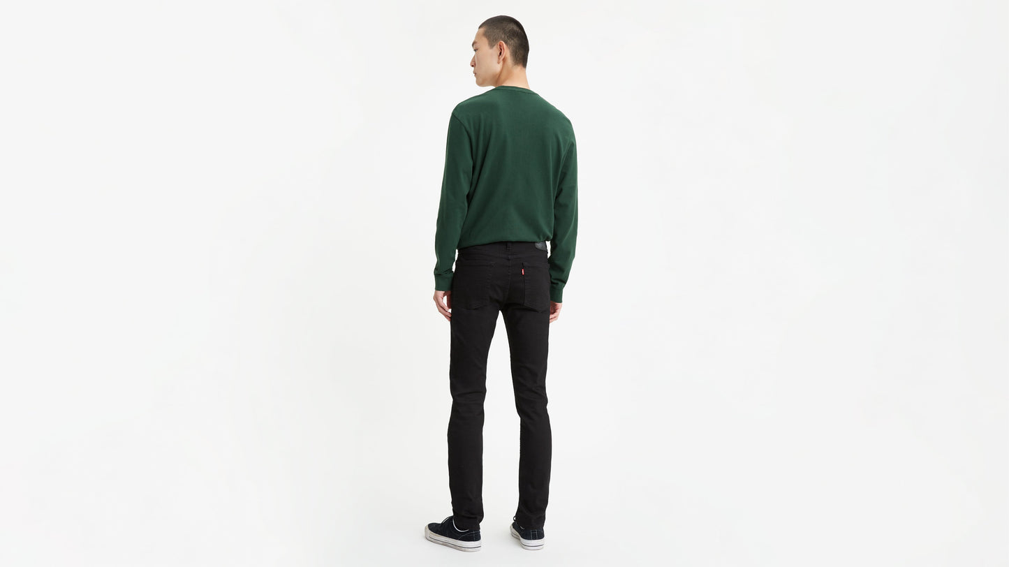 Back view of a man wearing black Levi’s skinny jeans, green sweatshirt, & black sneakers