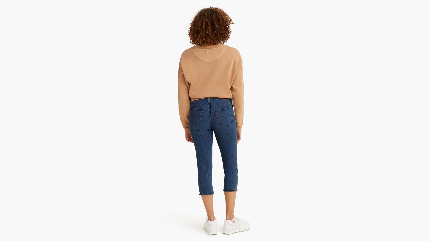 Woman in dark Levi’s capri jeans and tan sweatshirt, back view
