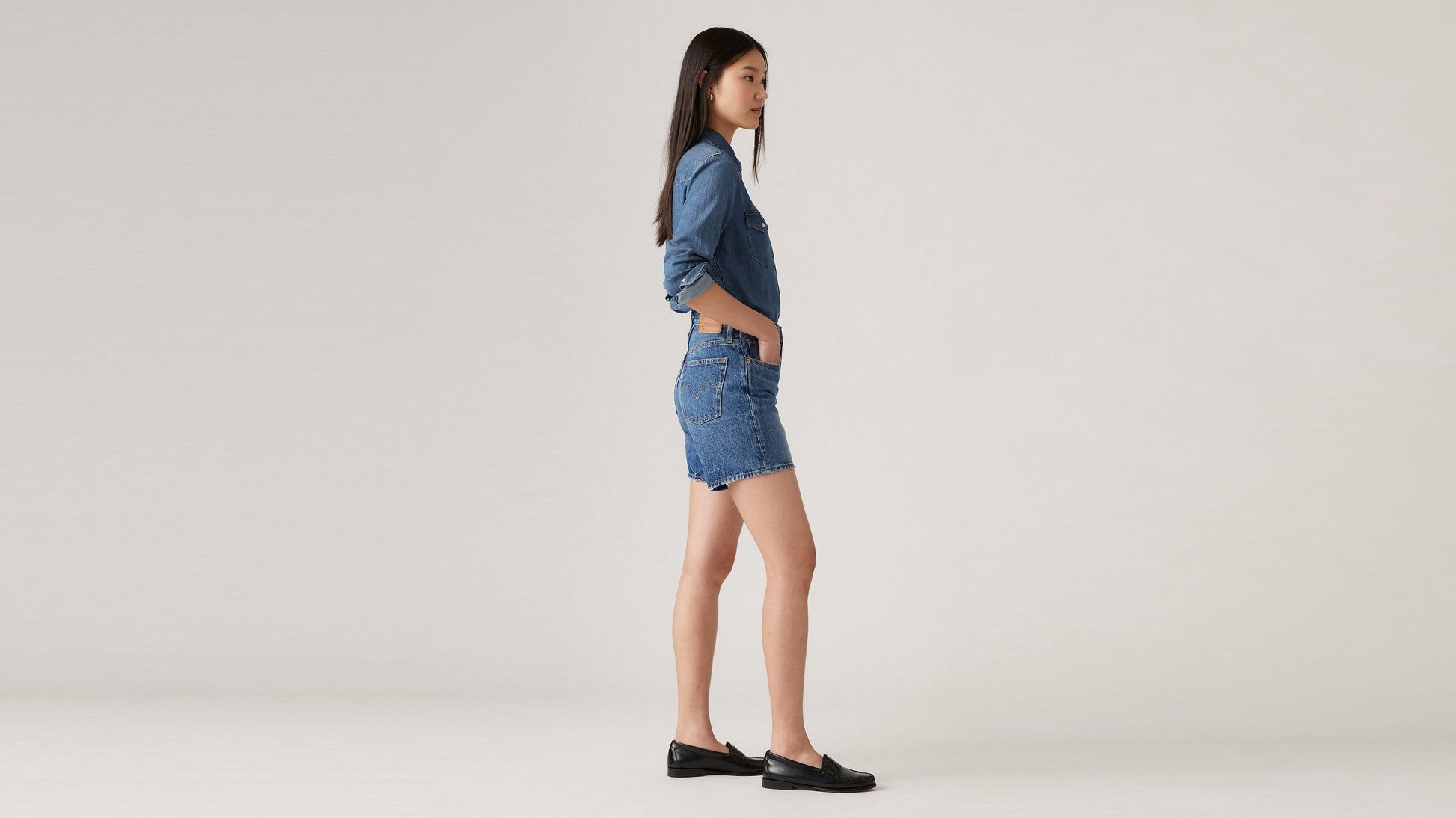 Side view of Woman in Levi's mid thigh shorts and long sleeves
