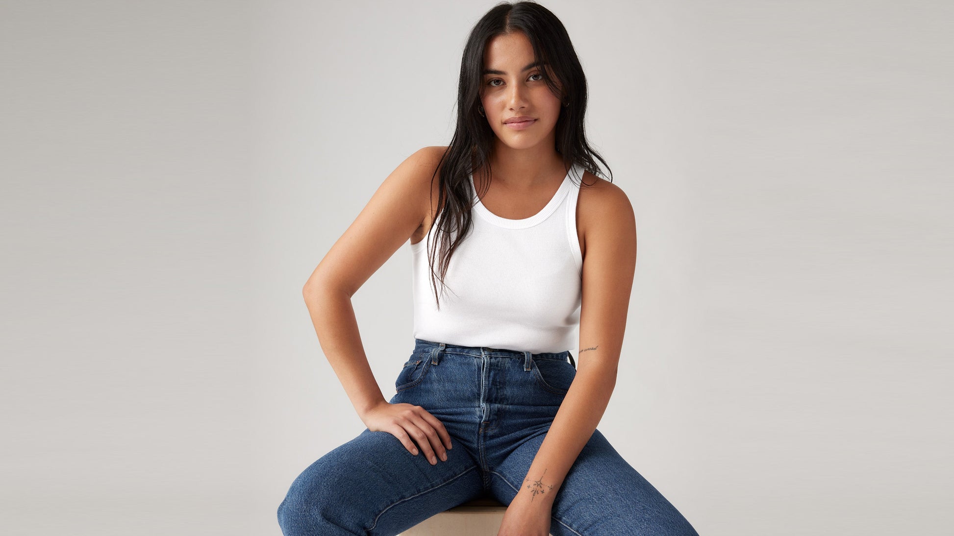 Woman wearing Levi's Women's Essential Racer Tank and blue jeans, seated